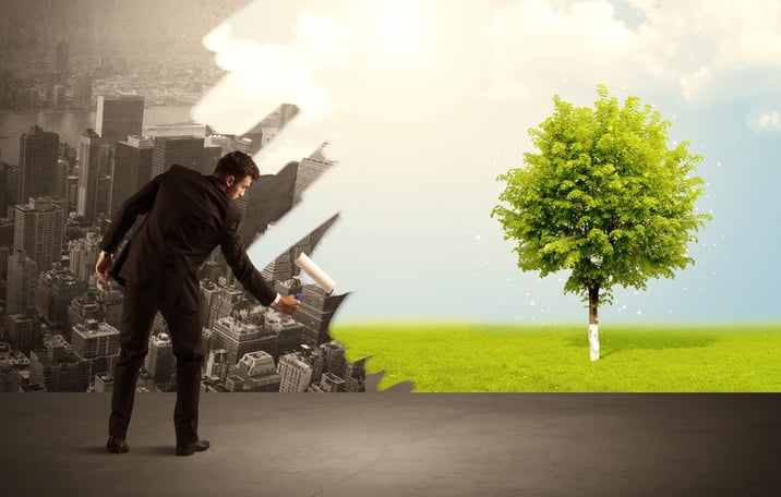 Businessman in elegant suit standing with his back, holding a roller and transforming the grey city landscape into green tree in bright nature environment concept